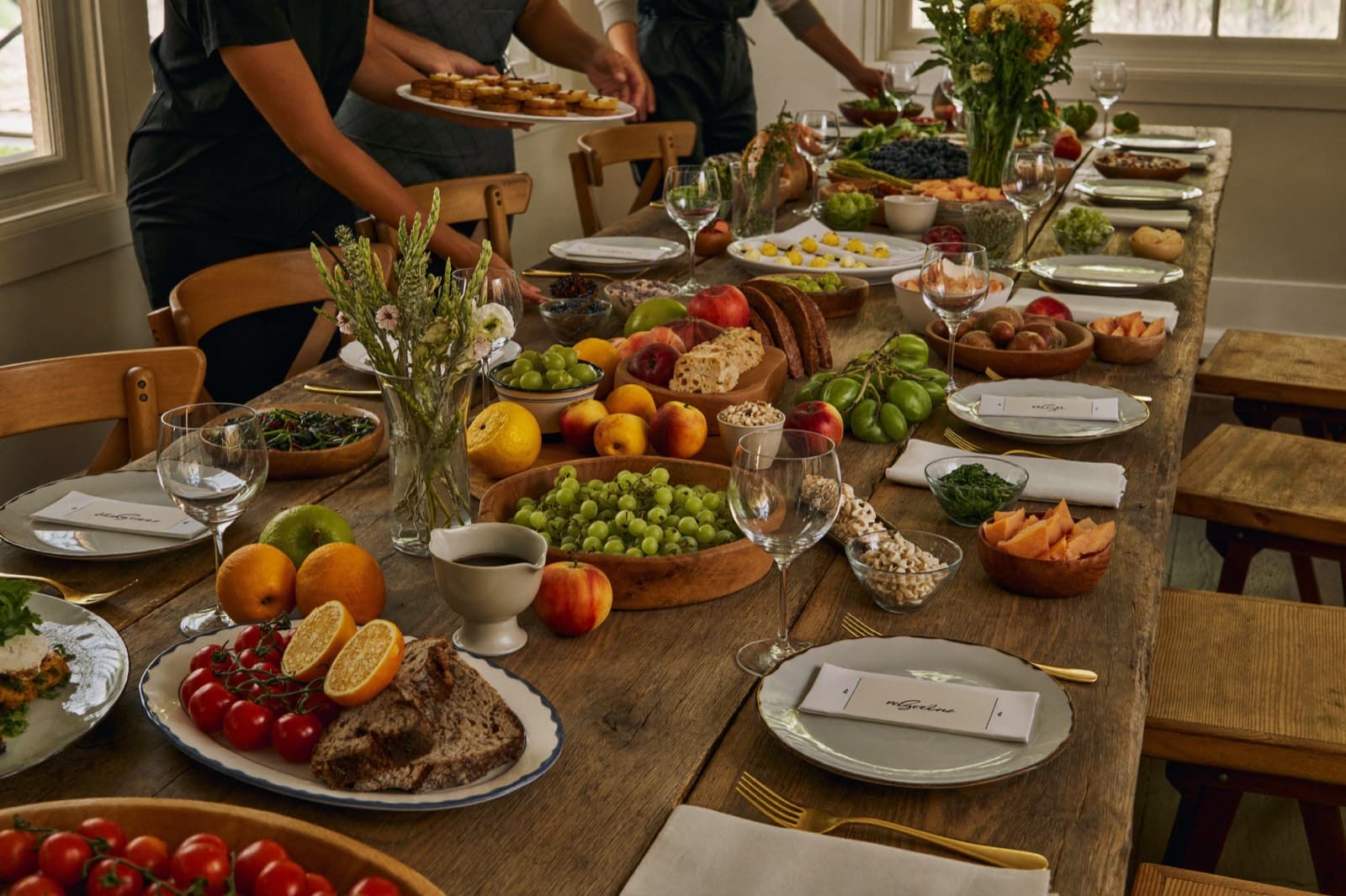 Staff dressing a long banquet table with platters and flowers